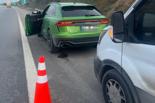 Otoyol emniyet şeridinde kapısı açık duran bir aracın arkasında güvenlik konisi; hemen yanında ekipmanlı servis aracı bekliyor.
